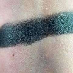 Close-up of fingertips applying shimmery bronze eye shadow from palette to eyelid