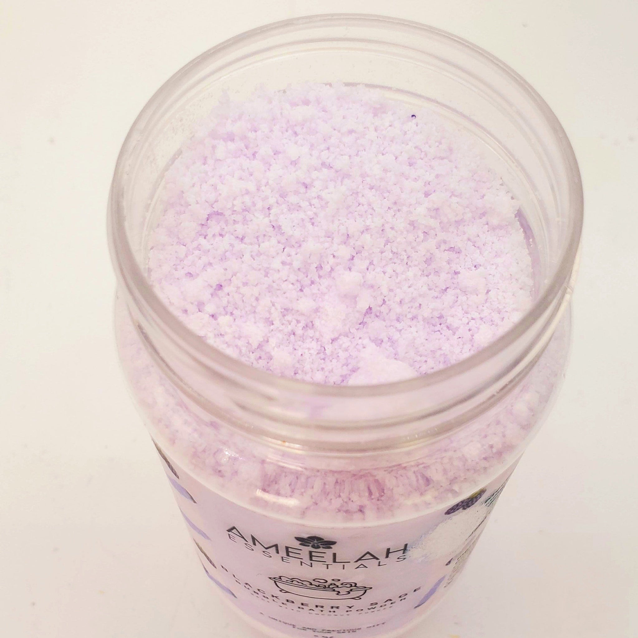 Bath powder in clear jar with light purple granules and Ameelah Essentials label visible
