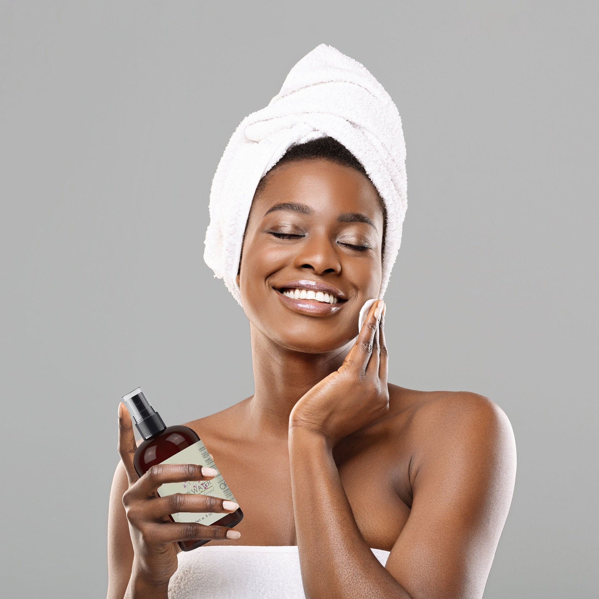 Facial toner bottle brown glass with black spray top held by woman in towel
