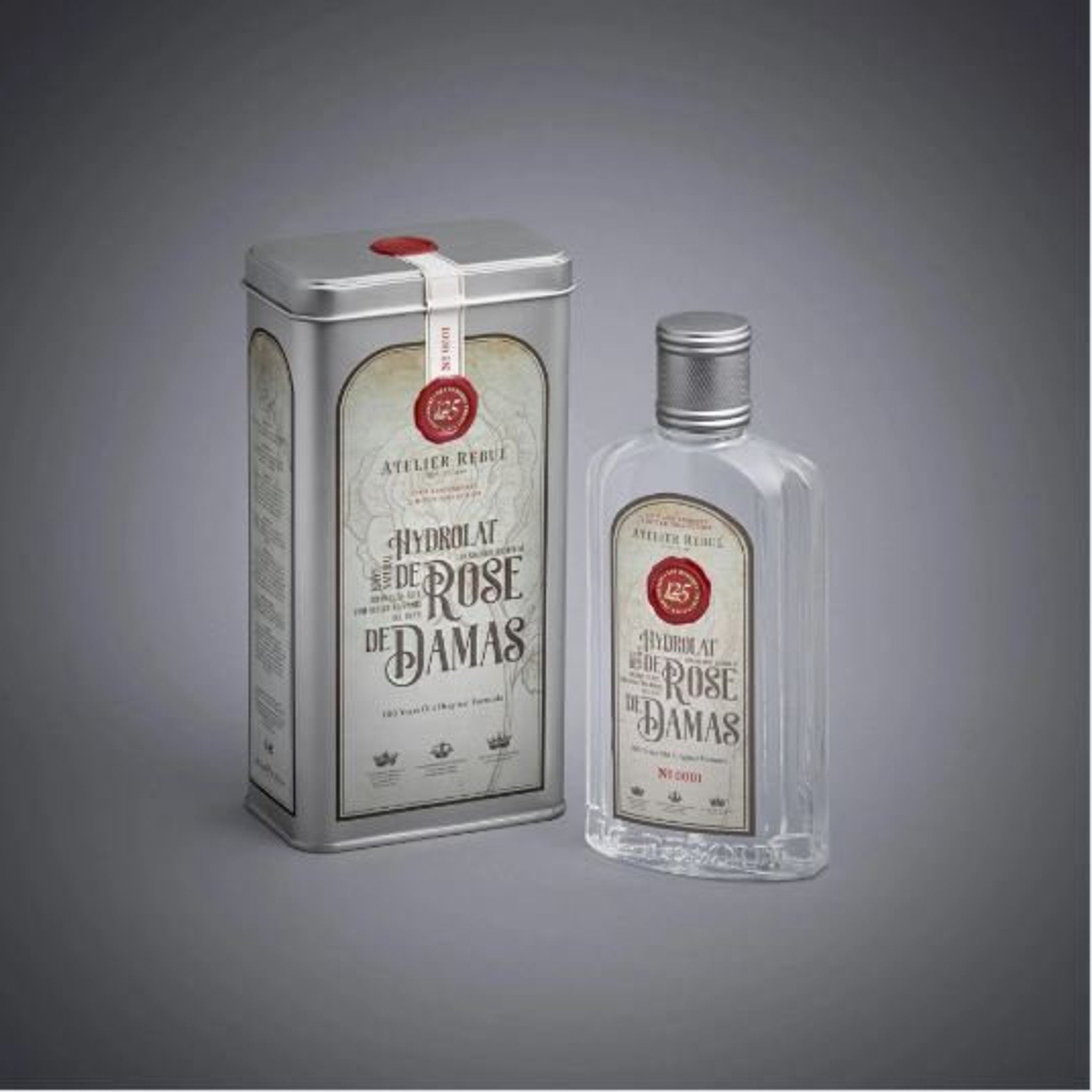 Perfume bottle and tin set with silver metal, clear glass, and Atelier Rebul label