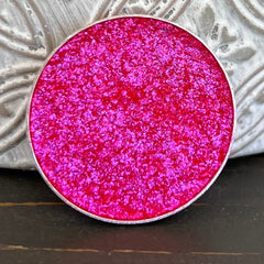 Close-up of Ring Around the Rosy holographic eyeshadow pan showing multi-chrome pink and gold shift with metallic finish