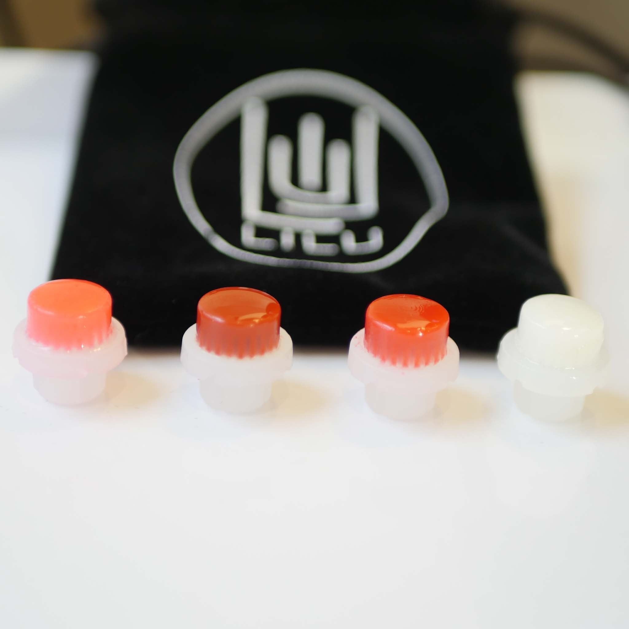 Caps with red and white tops, clear base, with black bag and LILU logo in background