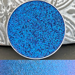 Close-up of Howl at the Moon multichrome eyeshadow pan showing shifting iridescent hues in compact.