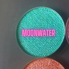 Metallic Moon Water eyeshadow pot with shimmering silver-blue powder and sleek black compact.