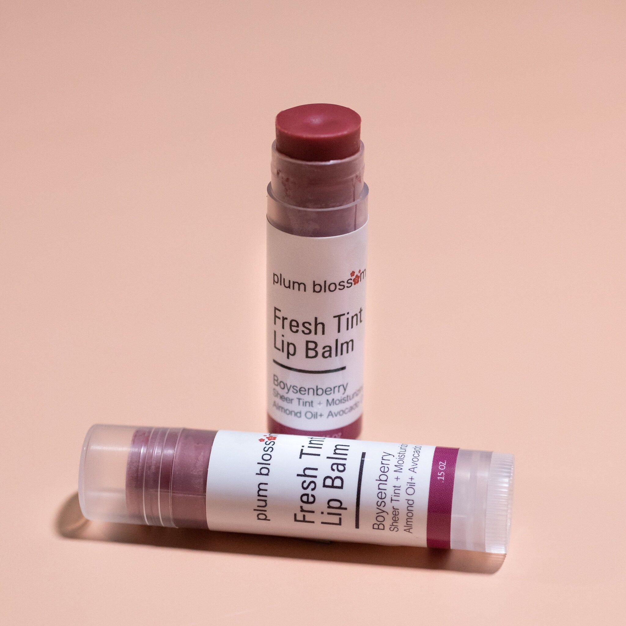Lip balm tubes with plum blossom branding, clear plastic, dark purple balm, and white label
