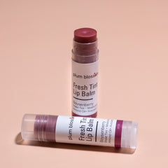 Lip balm tubes with plum blossom branding, clear plastic, dark purple balm, and white label