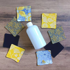 Reusable facial rounds with floral patterns in yellow, blue, and gray, next to a white bottle