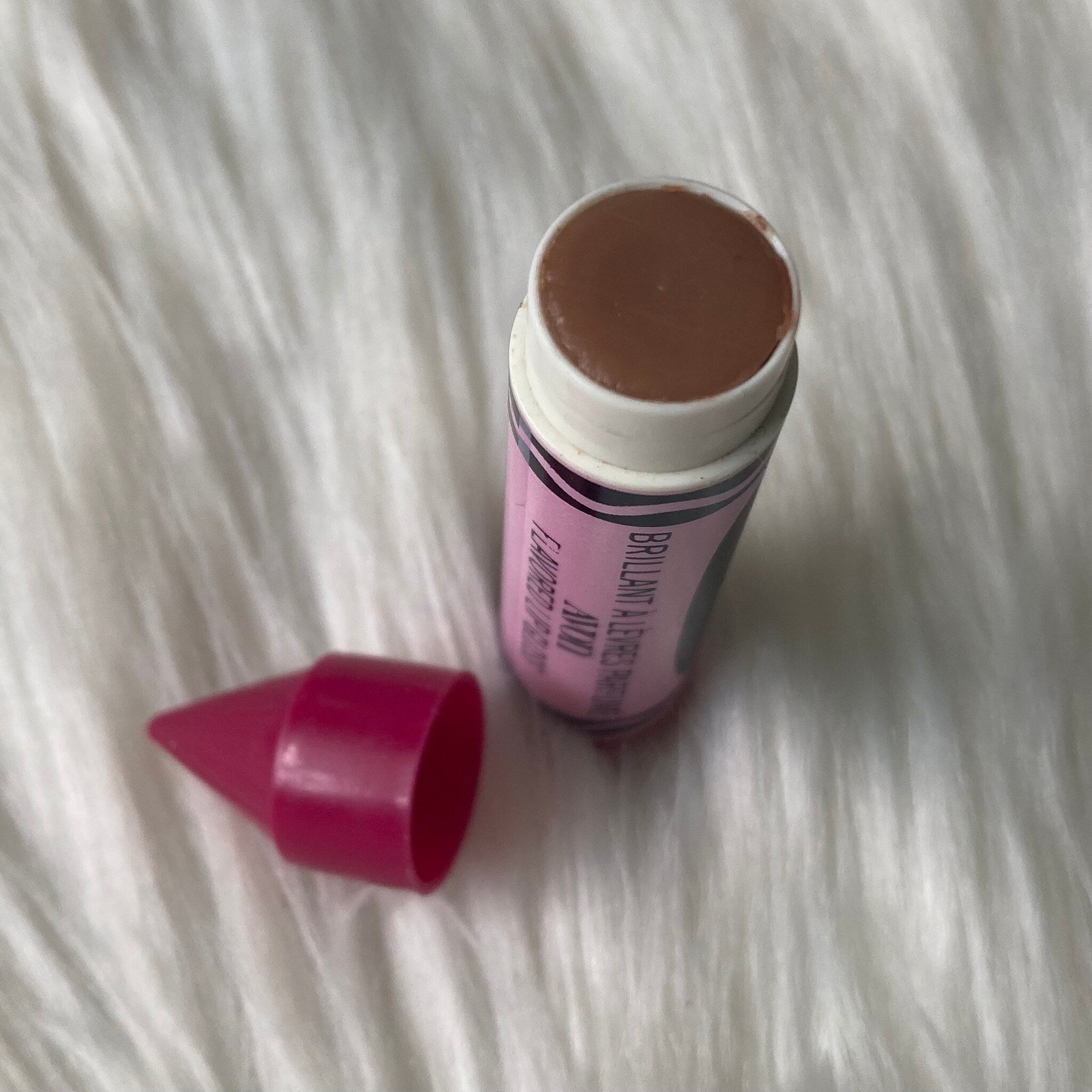 Close-up of a vintage 70s Avon lip gloss compact with mirrored lid and golden trim, showing creamy balm application