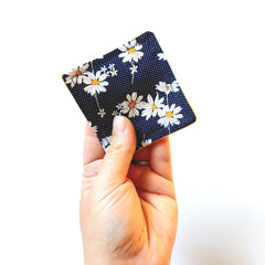 Coaster with daisy pattern, navy blue fabric, yellow trim, held in hand