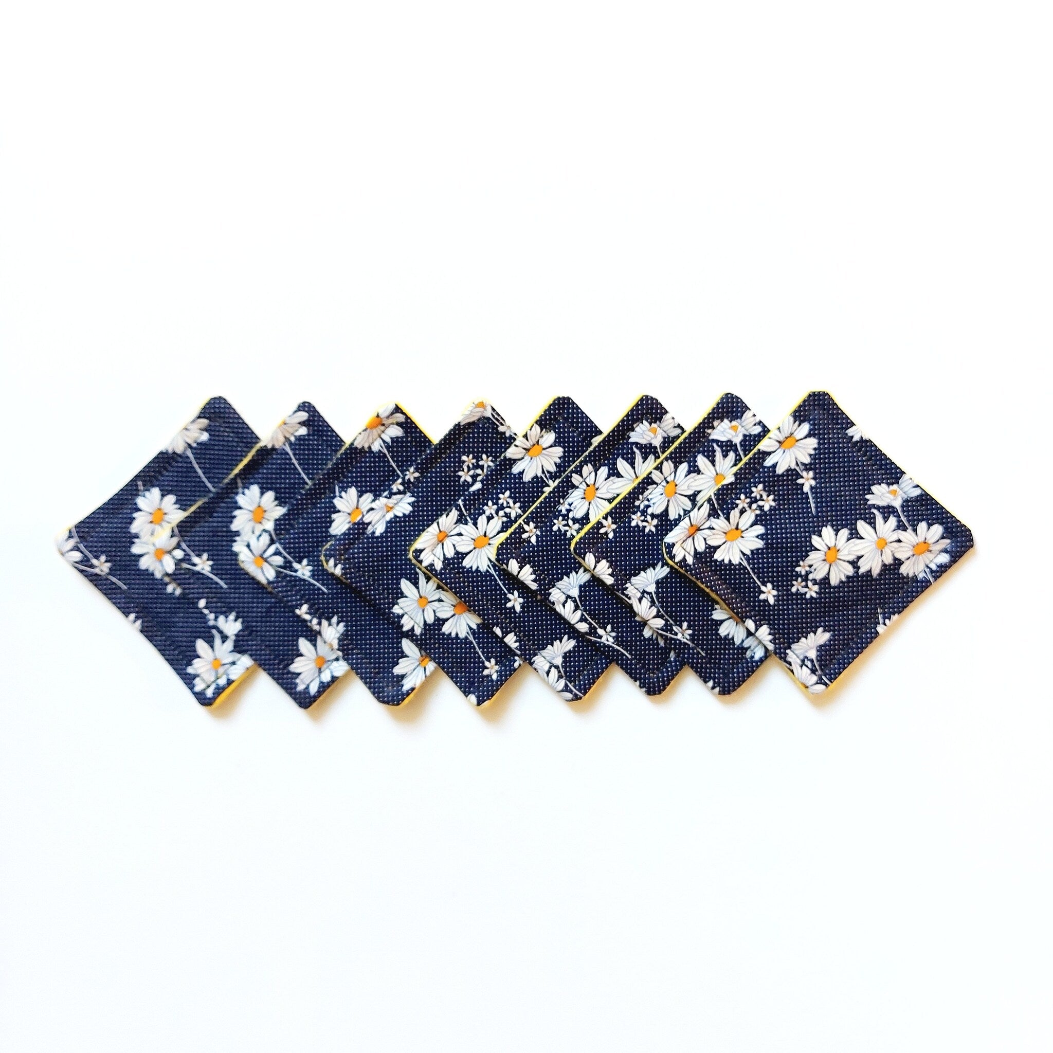 Coasters with navy floral pattern, yellow trim, and square shape, arranged in a row