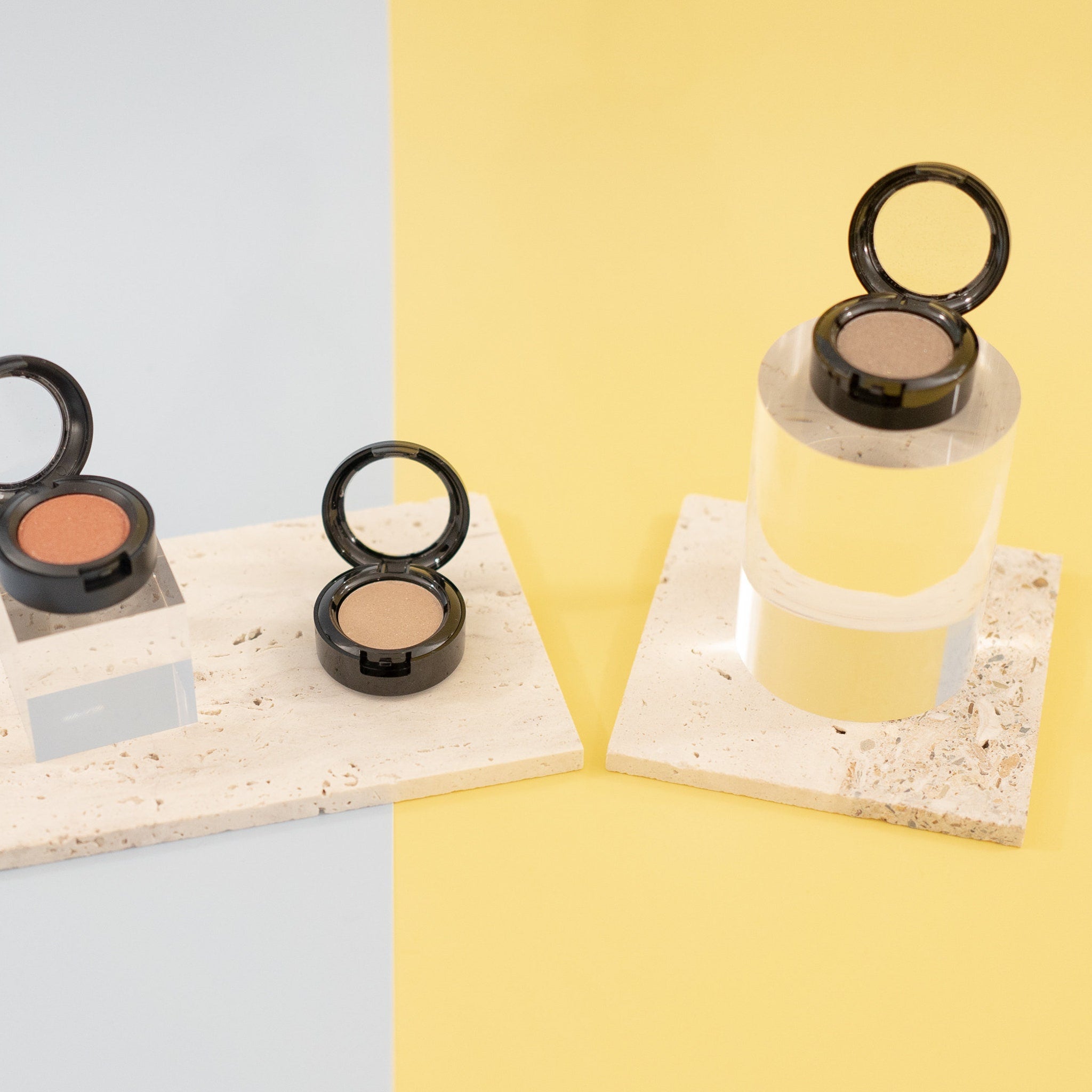 Close-up of a makeup brush applying sheer sequin gray mineral eyeshadow to eyelid for a shimmery finish.