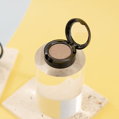 Single pan of light sheer sequin gray mineral eyeshadow with subtle shimmer in compact round case