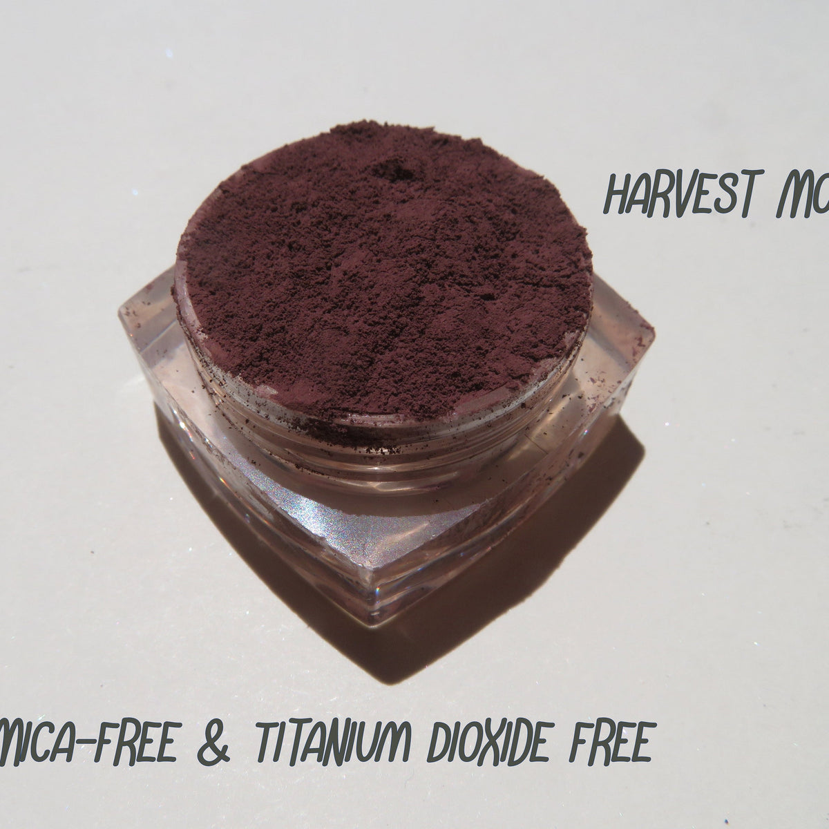 Matte dark brown purple mineral eyeshadow in loose powder form with vegan, cruelty-free label displayed.