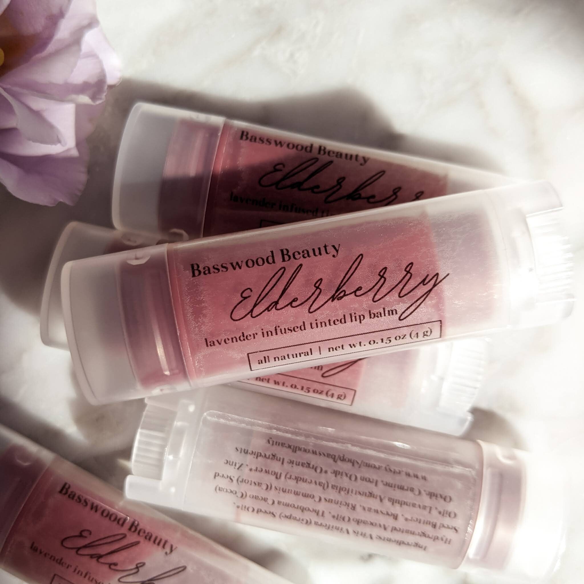 Lip balm tubes with pink tint and Basswood Beauty branding, lavender infused