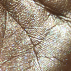 Close-up of shimmering champagne eyeshadow with smooth, buttery texture in compact case