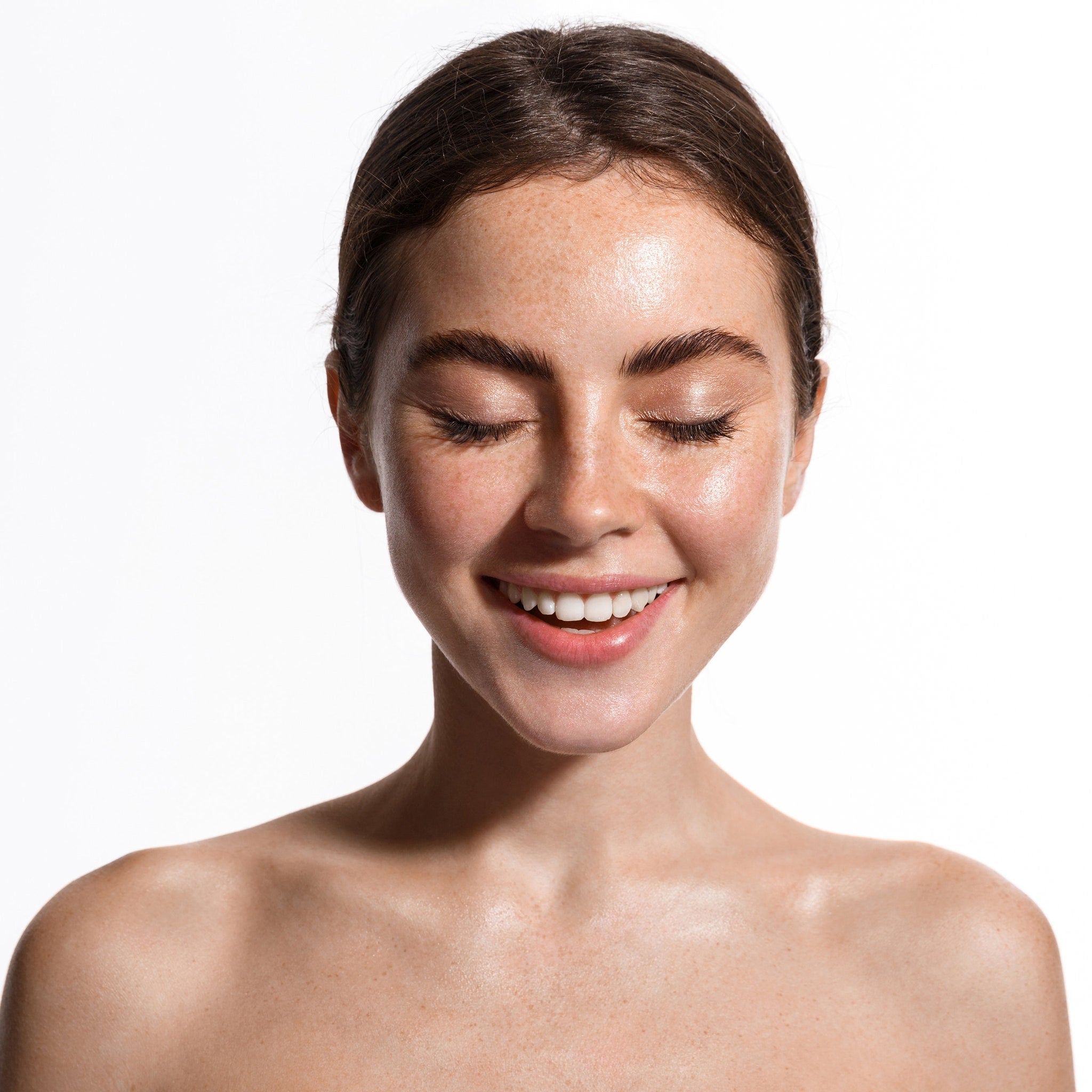 Woman's face with closed eyes, freckled skin, and smiling mouth on white background