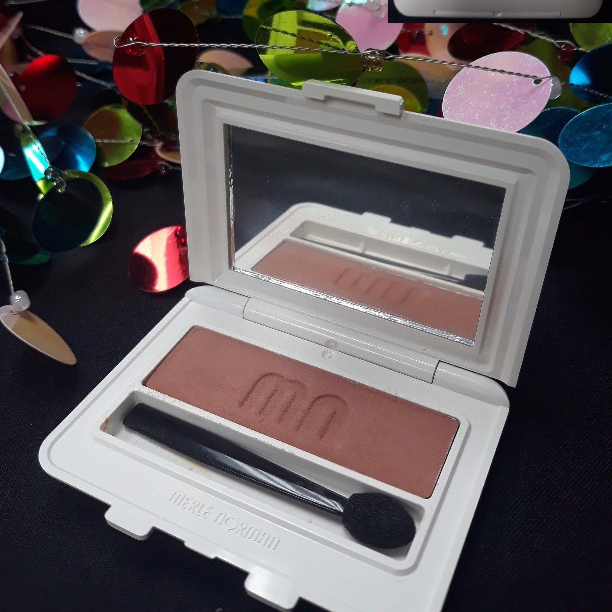 Side view of Merle Norman Luxiva single eye shadow compact in rich brown shade with sleek mirrored case