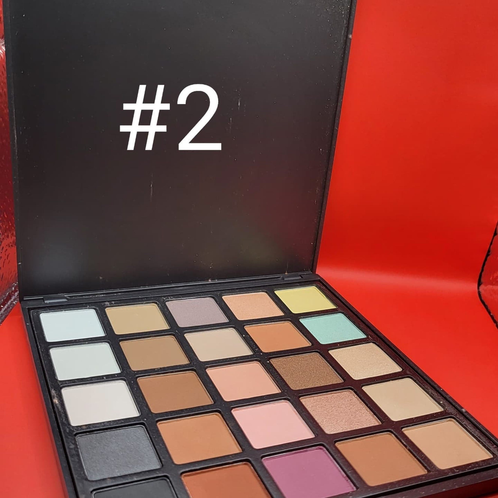 Open 25-color eyeshadow palette displaying vibrant matte and shimmer shades in rectangular pans