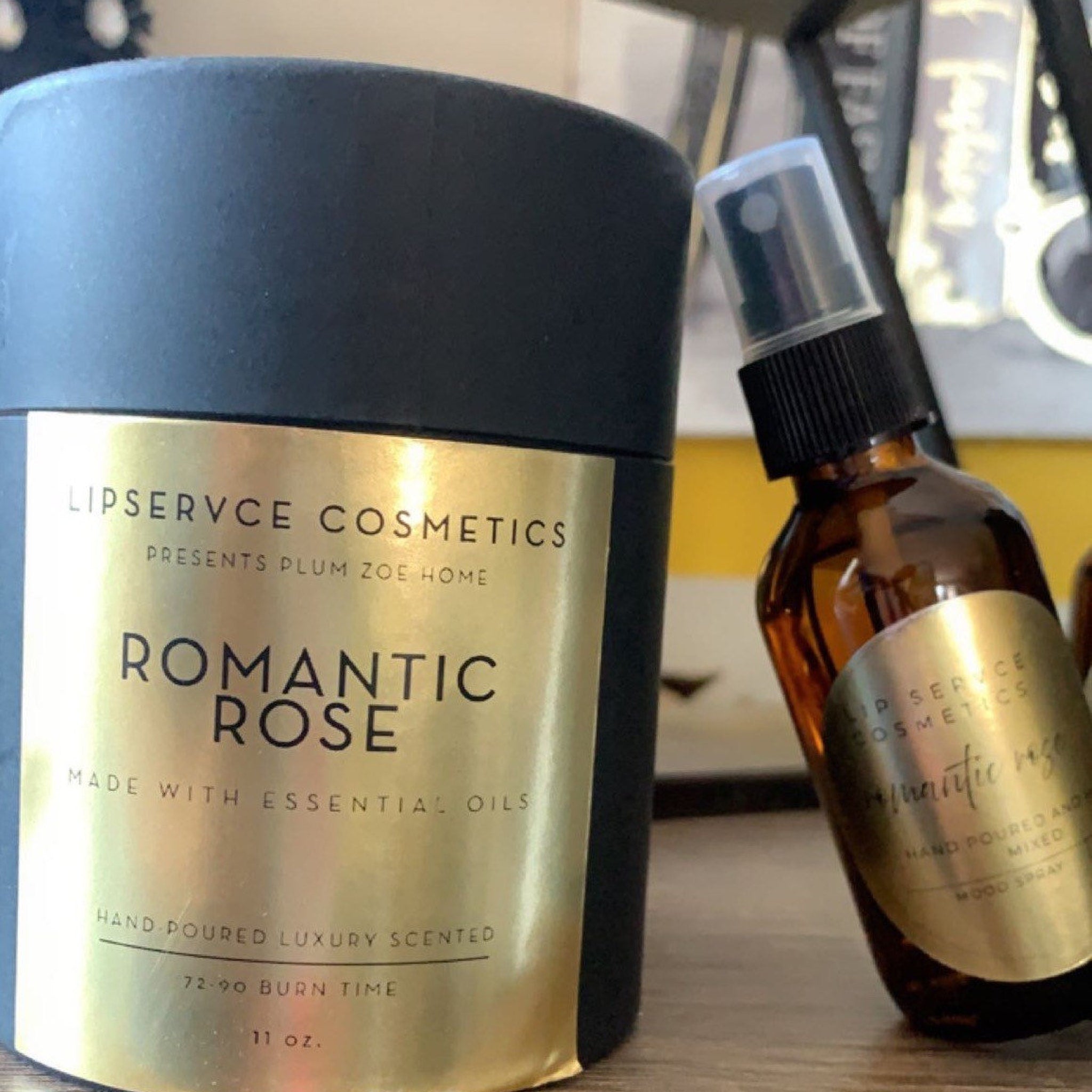 Candle and spray bottles with gold labels, black and amber glass, and "Romantic Rose" text