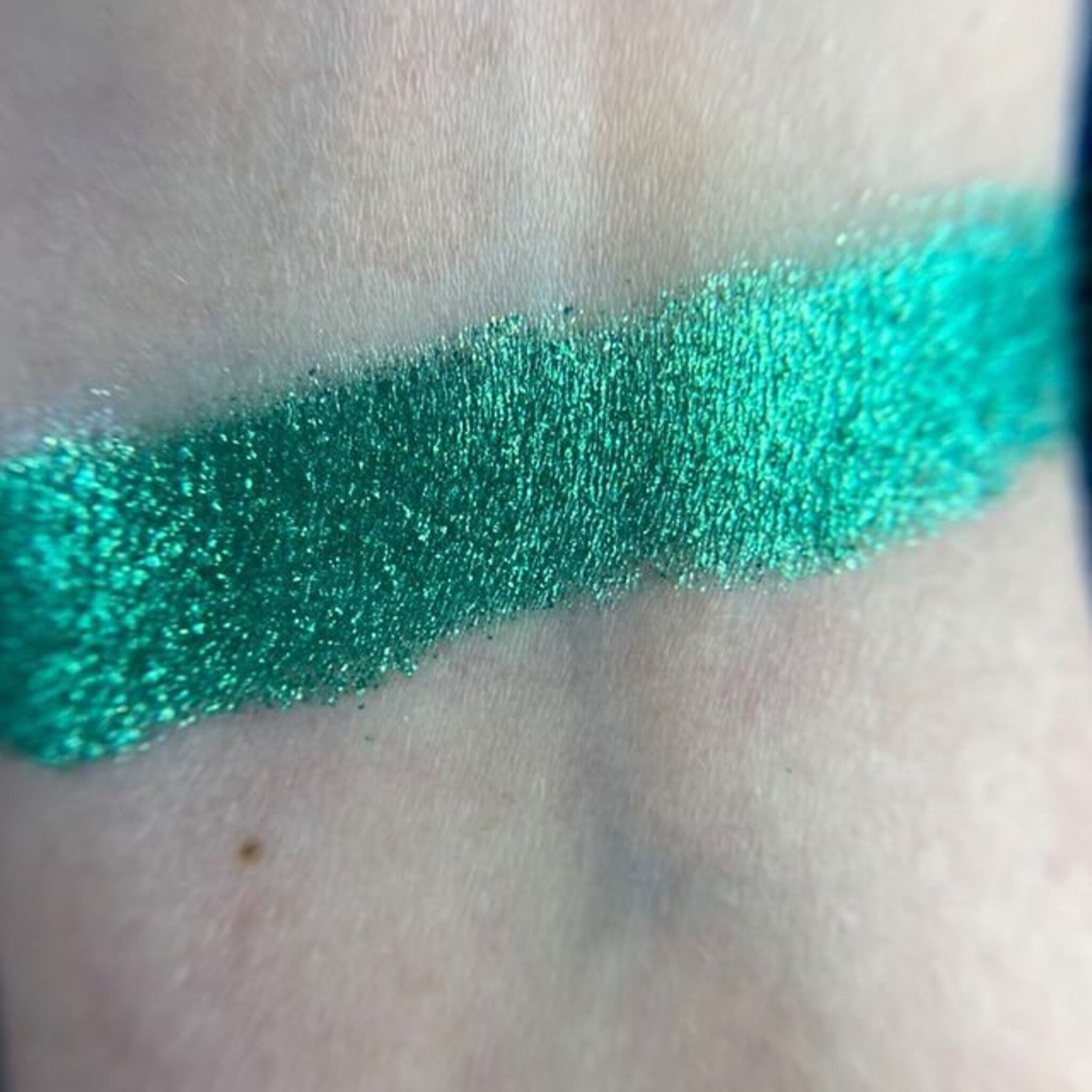 Close-up of zodiac-inspired eye shadow palette showing shimmering celestial blue and deep cosmic purple shades