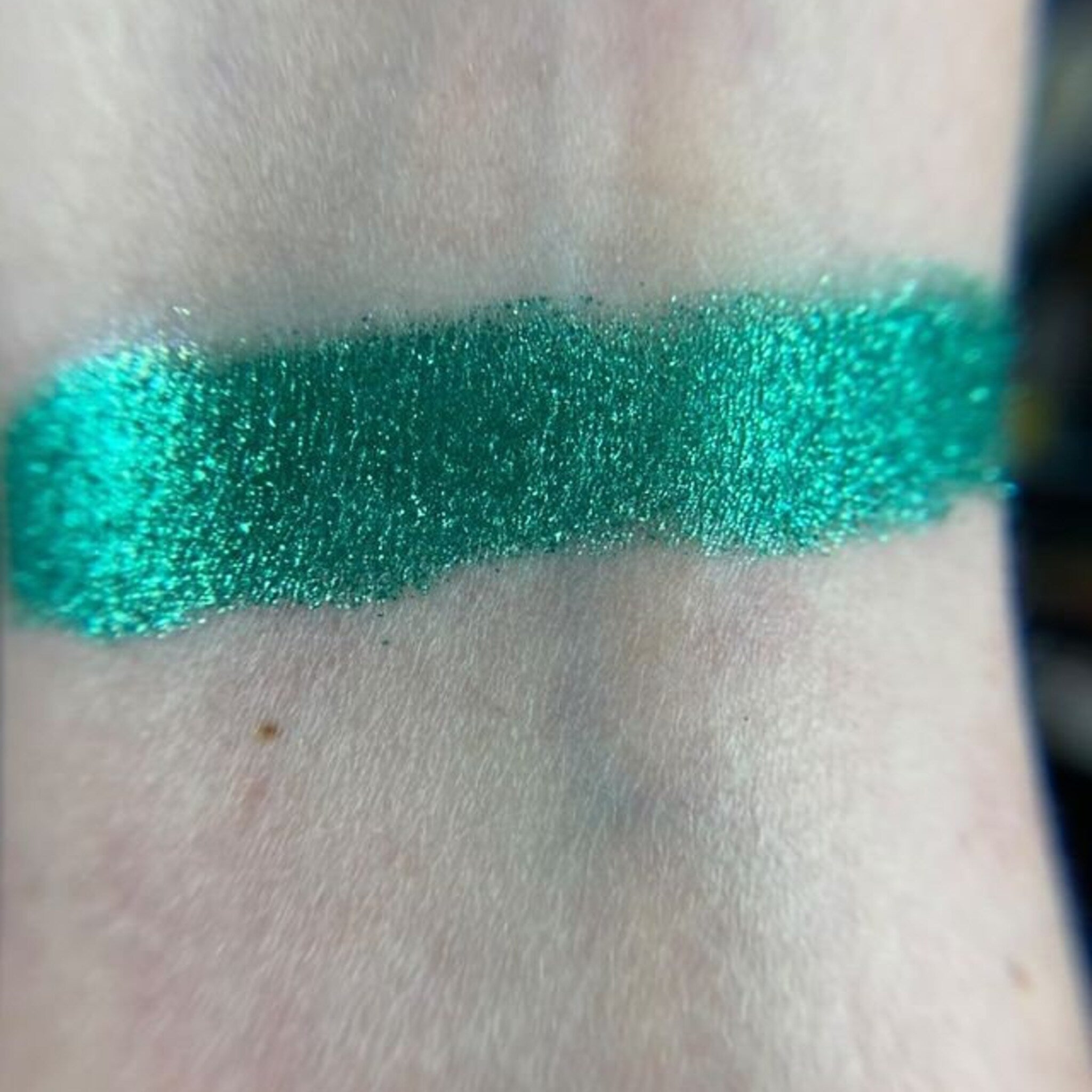Close-up of fingertips applying shimmering zodiac-inspired eyeshadow in deep blue and gold tones
