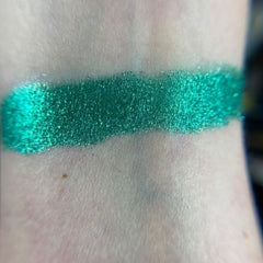 Close-up of fingertips applying shimmering zodiac-inspired eyeshadow in deep blue and gold tones
