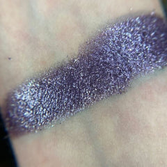Close-up of shimmery bronze and navy eyeshadows in a sleek black palette with star embossing
