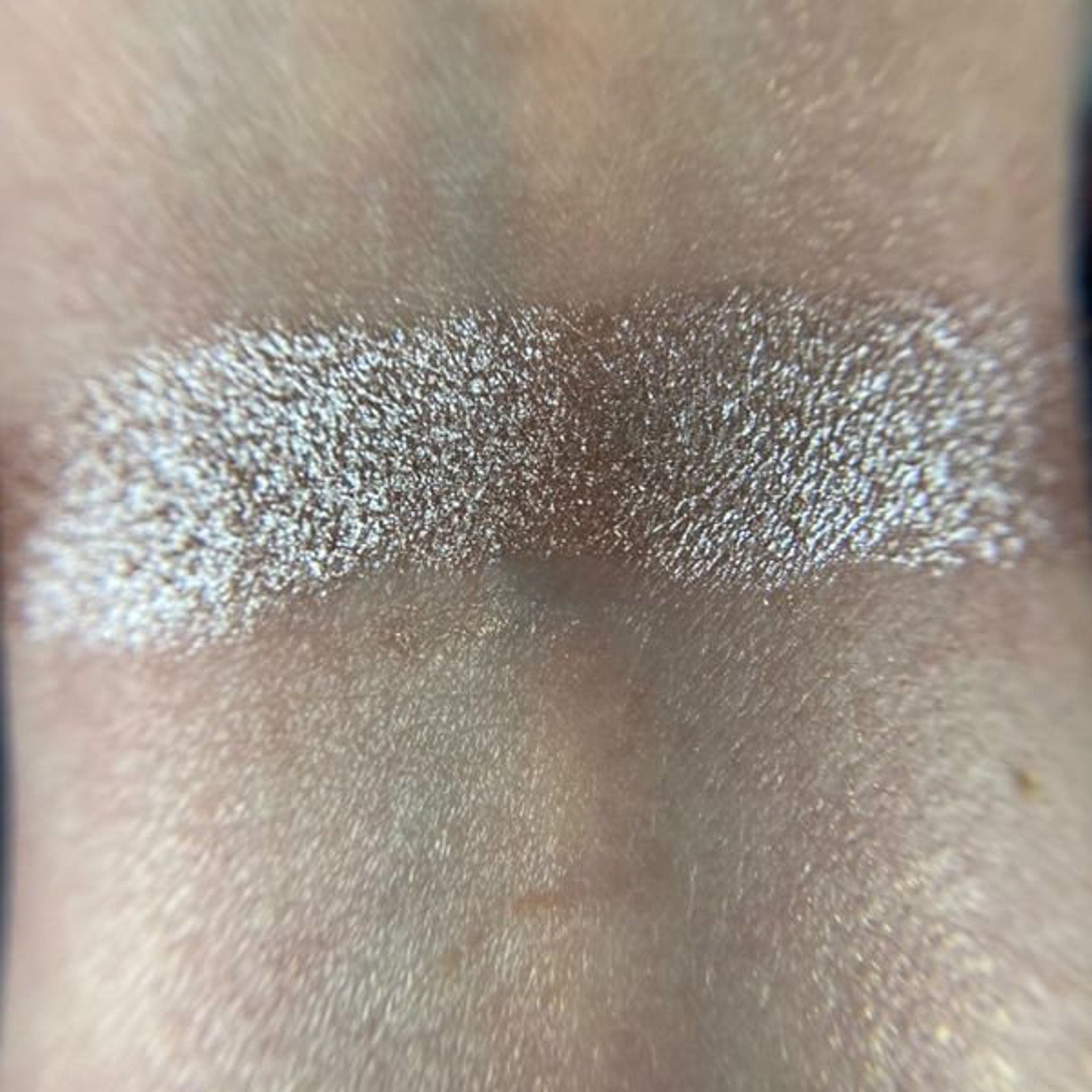 Woman applying shimmery champagne eye shadow with fingertip to eyelid for a glowing makeup look