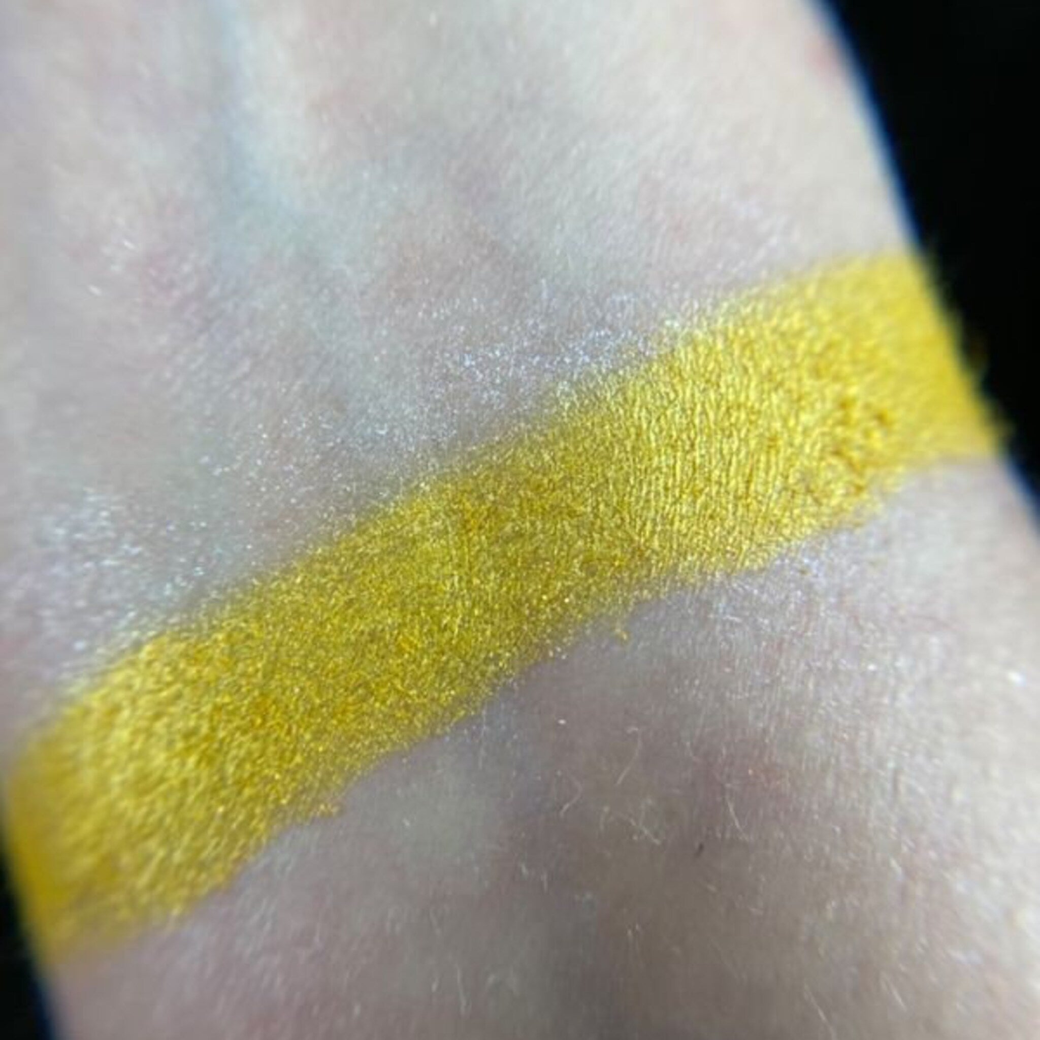 Yellow eyeshadow swatch on skin, showing bright yellow color and shimmer texture