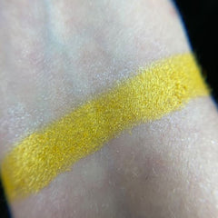 Yellow eyeshadow swatch on skin, showing bright yellow color and shimmer texture