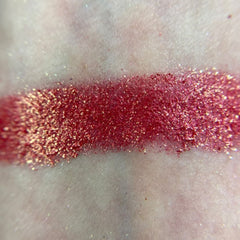 Close-up of a hand applying shimmery taupe eyeshadow from the M80 palette with a fluffy brush