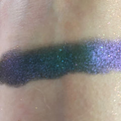 Close-up of fingertips applying shimmery taupe eye shadow to eyelid with soft blending brush