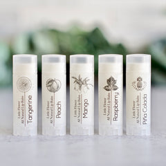 Lip balm tubes in white with fruit illustrations and black text, The Little Flower Soap Co brand