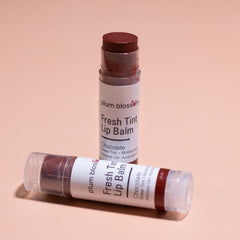 Lip balm with brown tint, clear tube, and Plum Blossom Apothecary branding