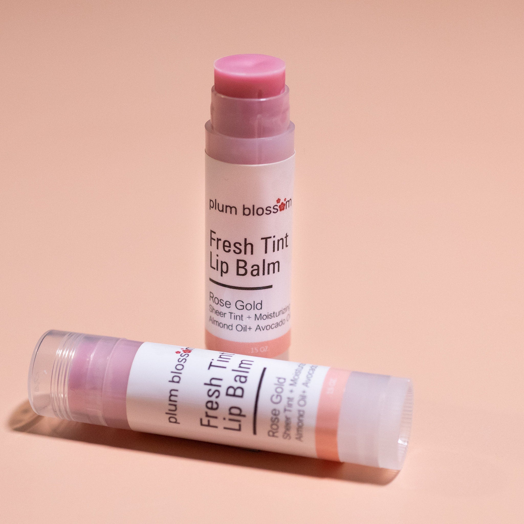 Lip balm tubes with pink tint and white label, plum blossom brand visible on packaging