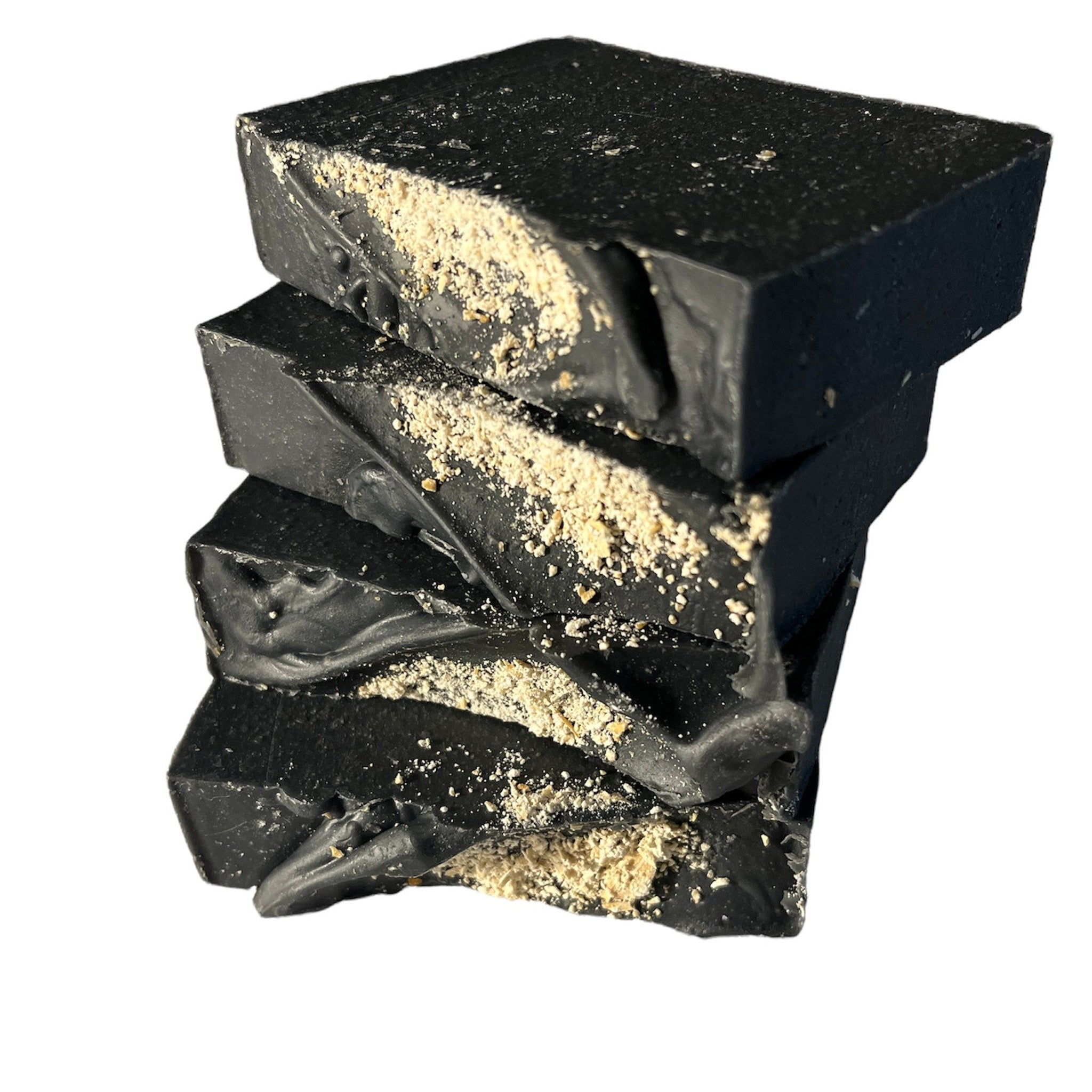 Black soap bars with tan flecks, stacked on white background