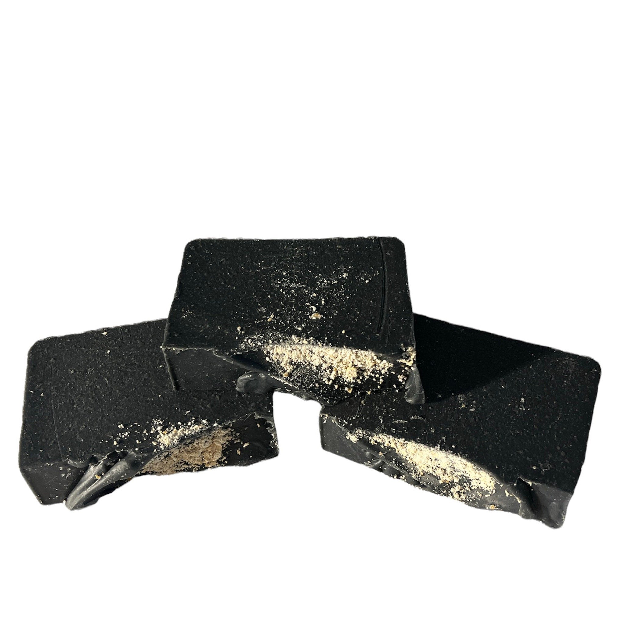 Black soap bars with speckled texture and rough edges, stacked together