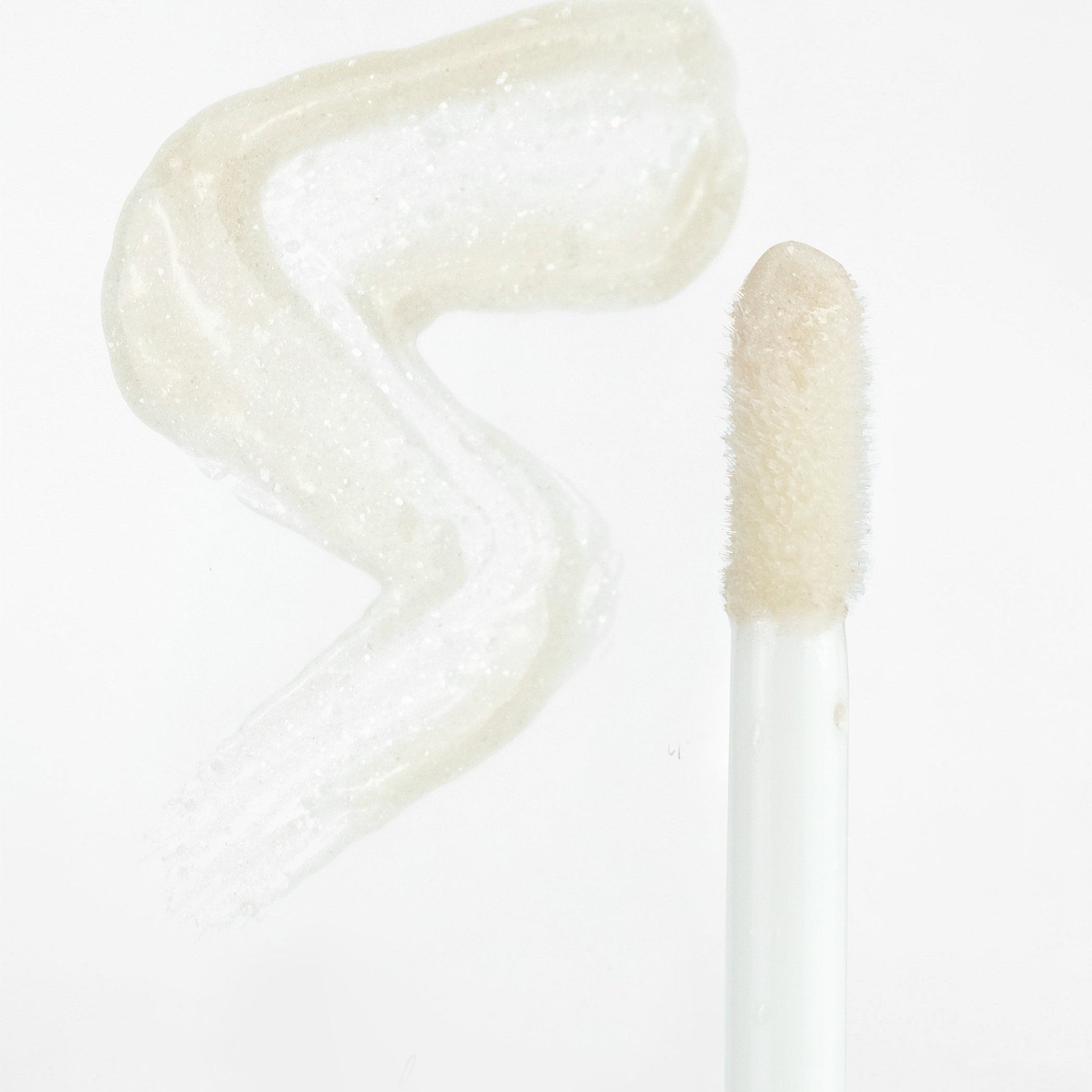 Lip gloss swatch with clear, shimmery, light beige liquid and applicator with white handle and soft tip