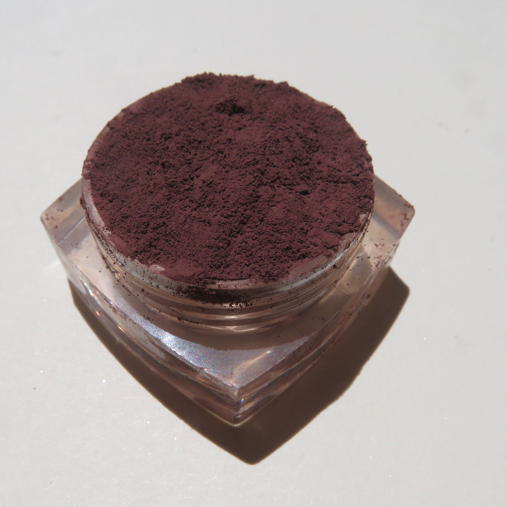 Hand applying matte dark brown purple mineral eyeshadow with a fluffy brush for a blended eye makeup look