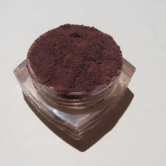 Hand applying matte dark brown purple mineral eyeshadow with a fluffy brush for a blended eye makeup look