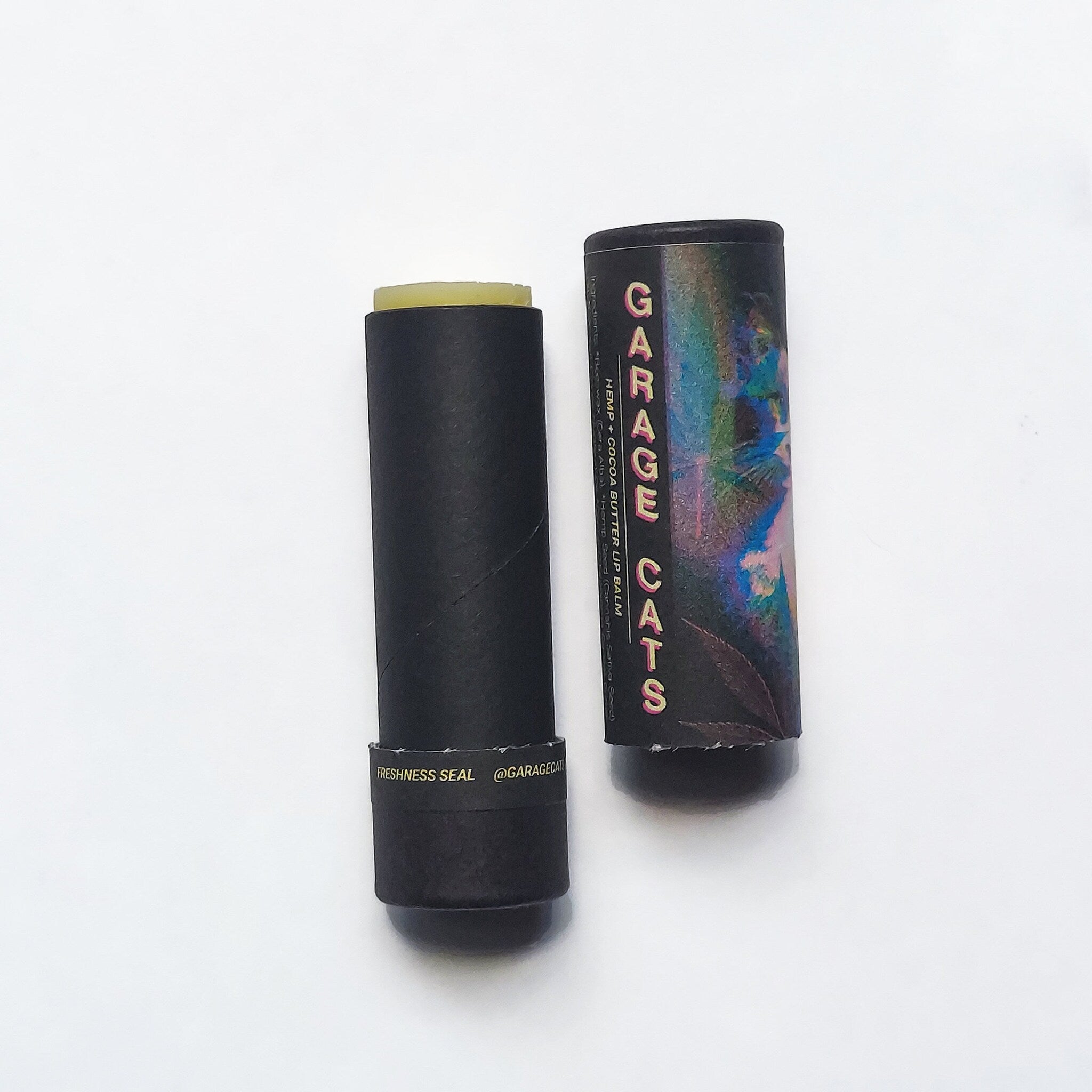 Lip balm tube with black paper casing, Garage Cats branding, and exposed balm product