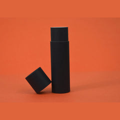 Black cylindrical container with matching lid on orange background, matte finish
