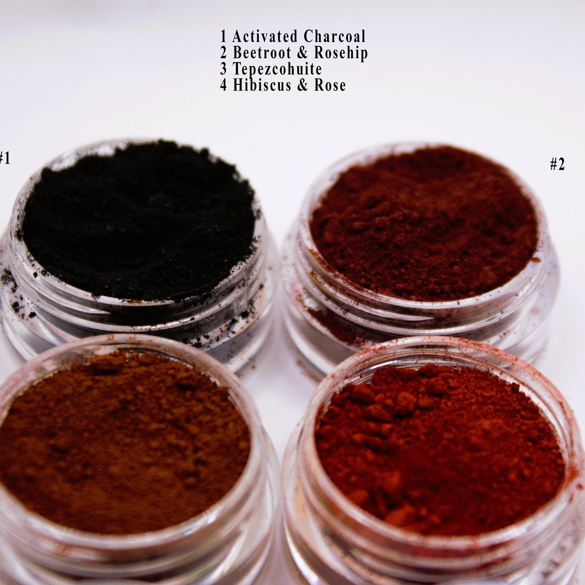Powdered products in clear jars, black, brown, and red, on white background