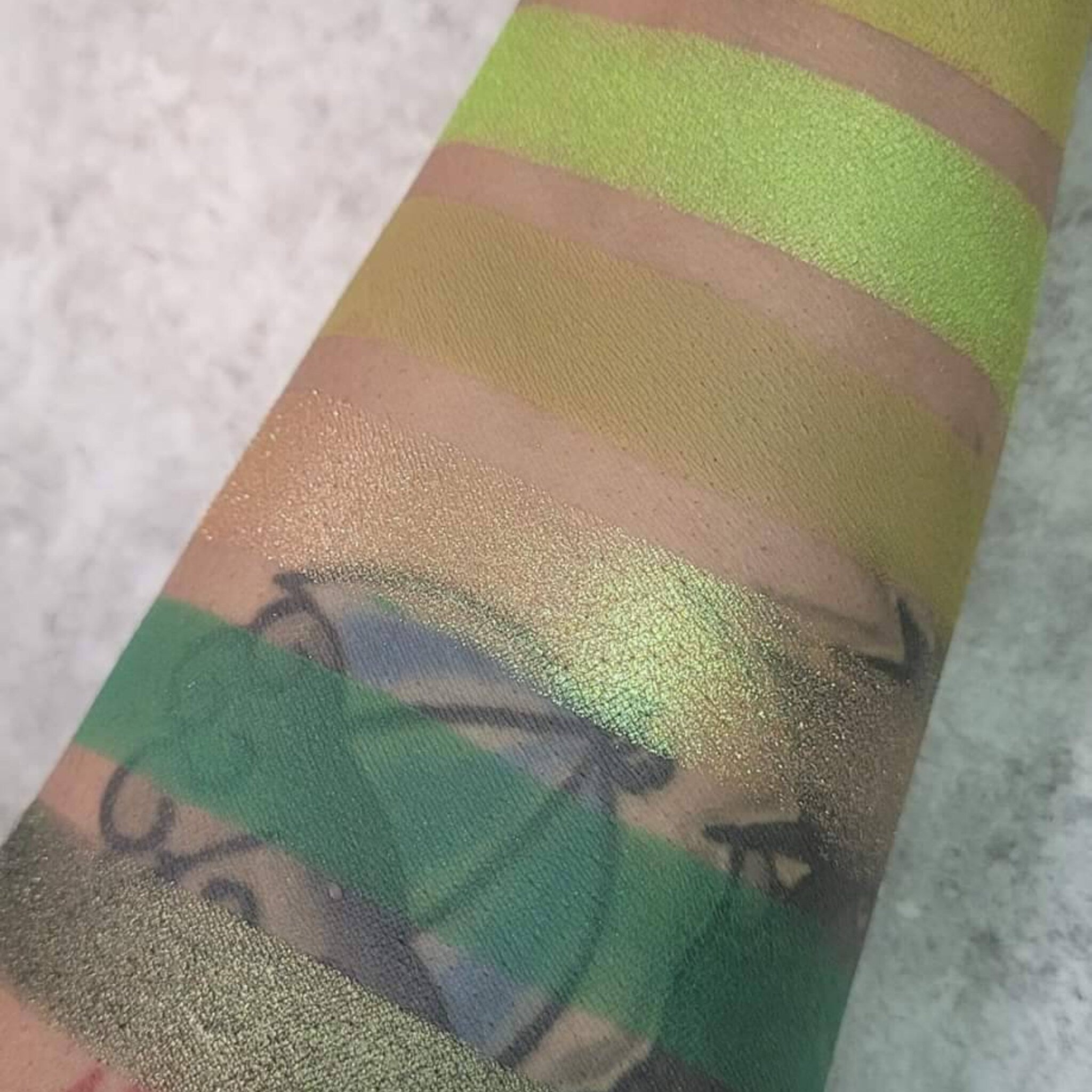 Side view of six green eyeshadow pans in earthy herb-inspired shades with matte and shimmer finishes