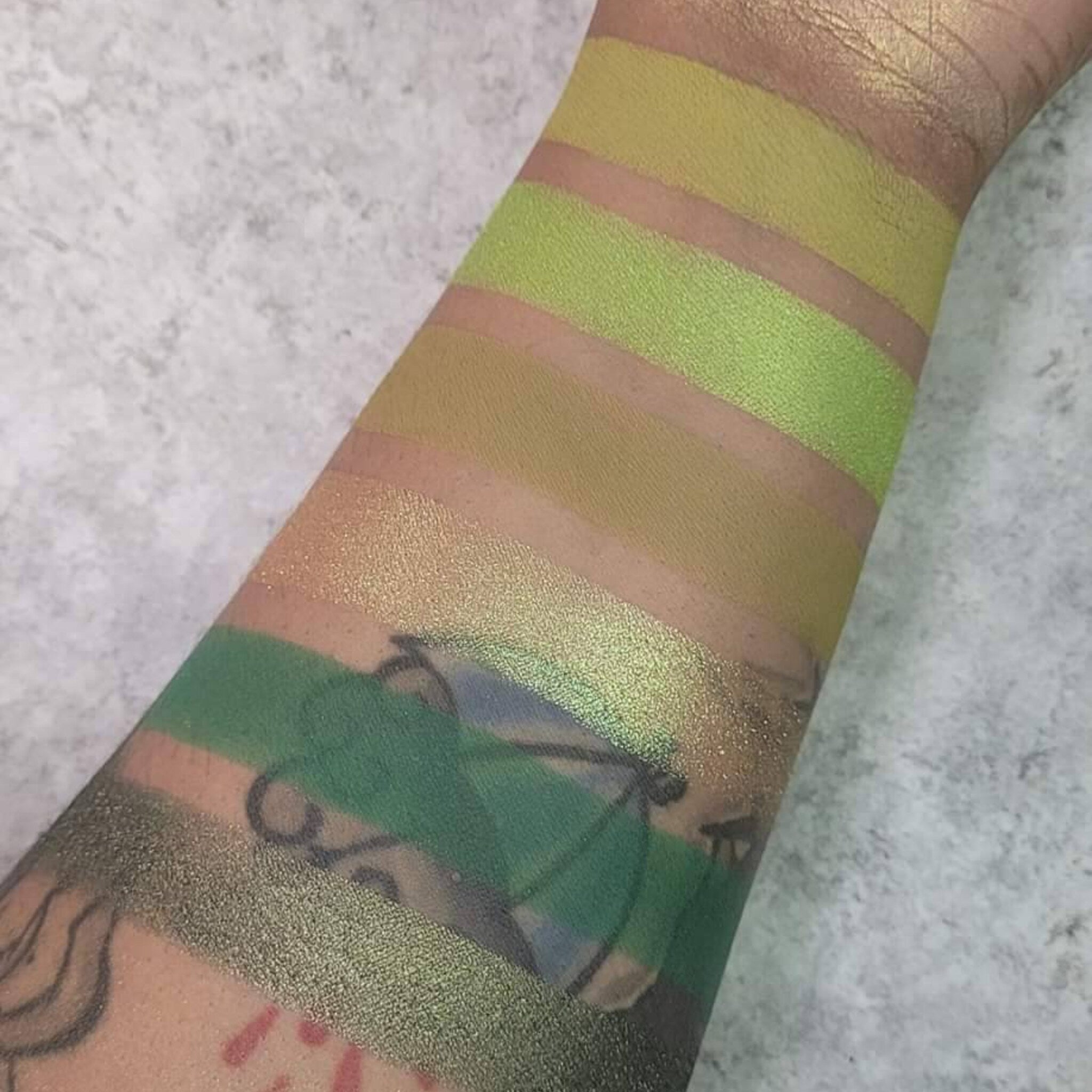 Side view of six green eyeshadow pans in earthy herb-inspired shades with matte and shimmer finishes