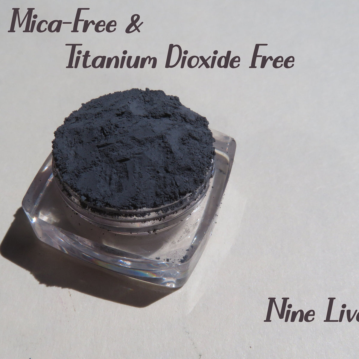 Dark gray matte loose mineral eyeshadow in a round black jar with silver lid, vegan and cruelty-free makeup pigment