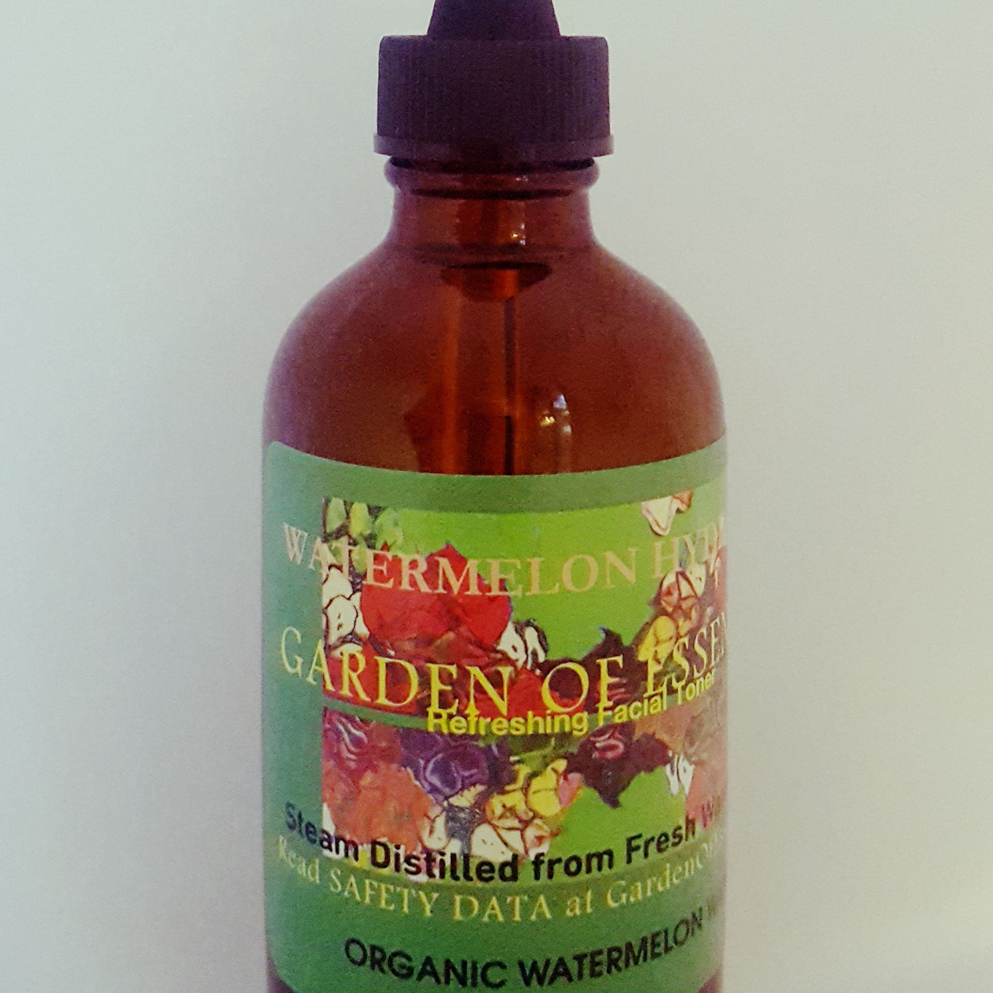 Facial toner bottle, brown glass bottle with black cap, green label with Garden of Essences text