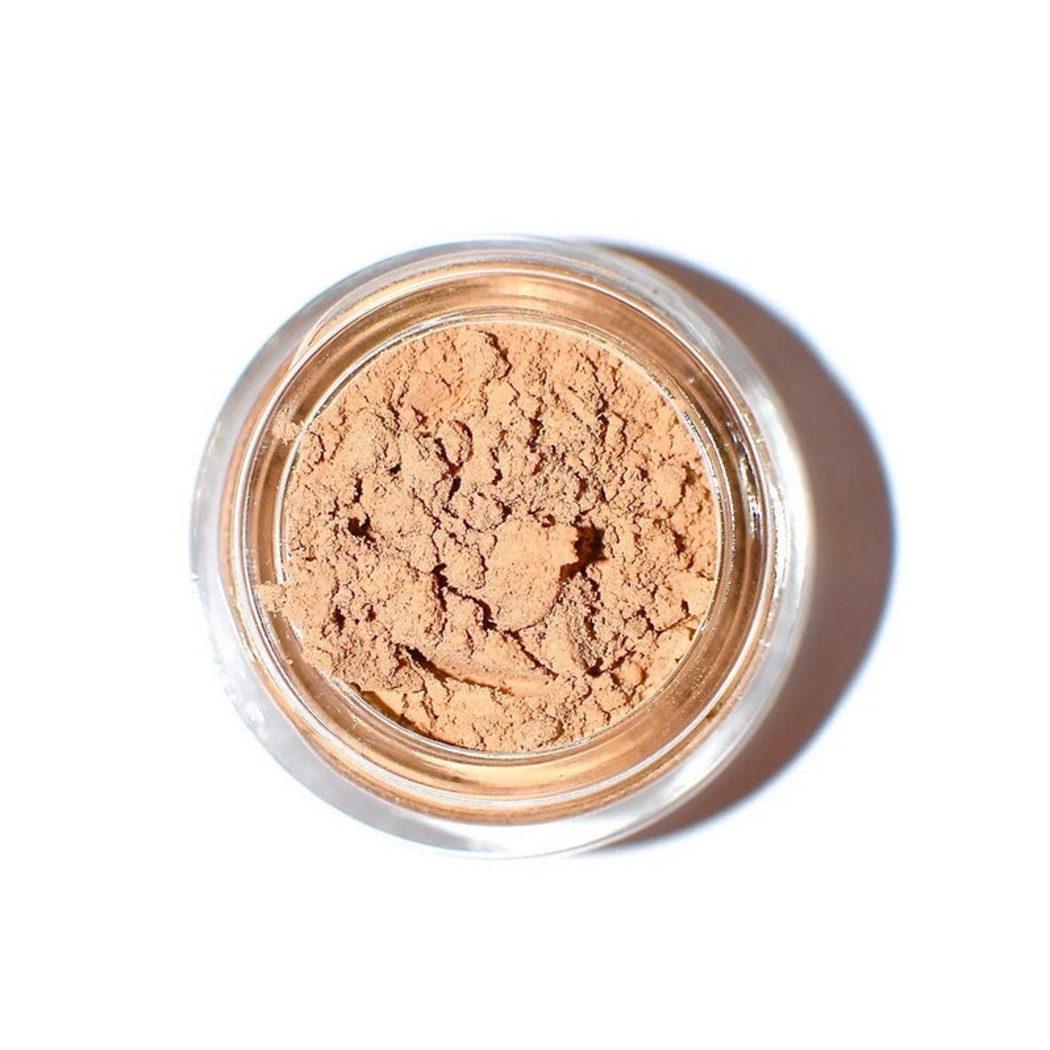 Close-up of cave-inspired eye shadow palette with earthy bronze and taupe shades in sleek black compact