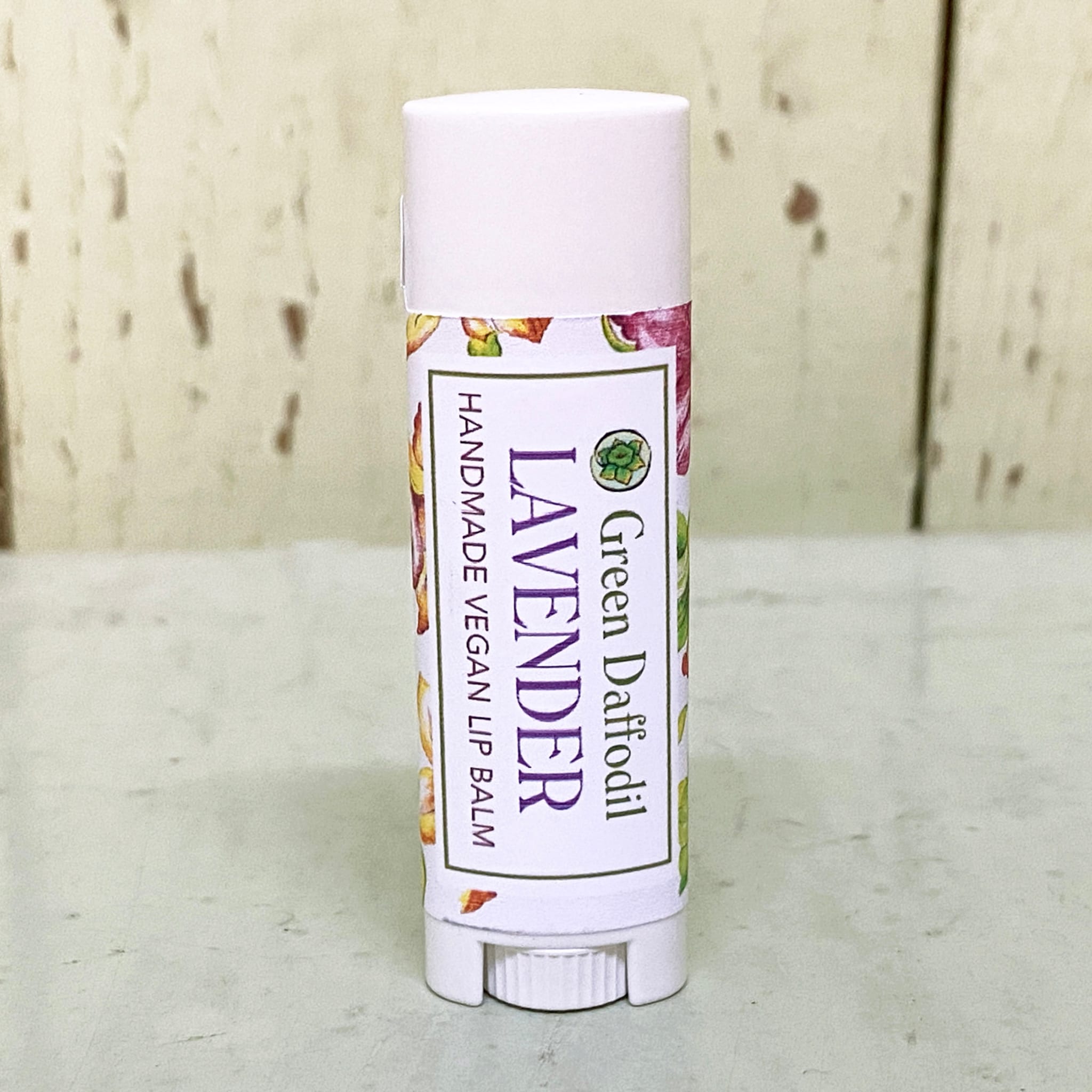 Lip balm tube with white cap, floral pattern, and Green Daffodil brand label