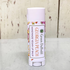 Lip balm tube with white cap, floral label, and "Georgia Peach" text visible